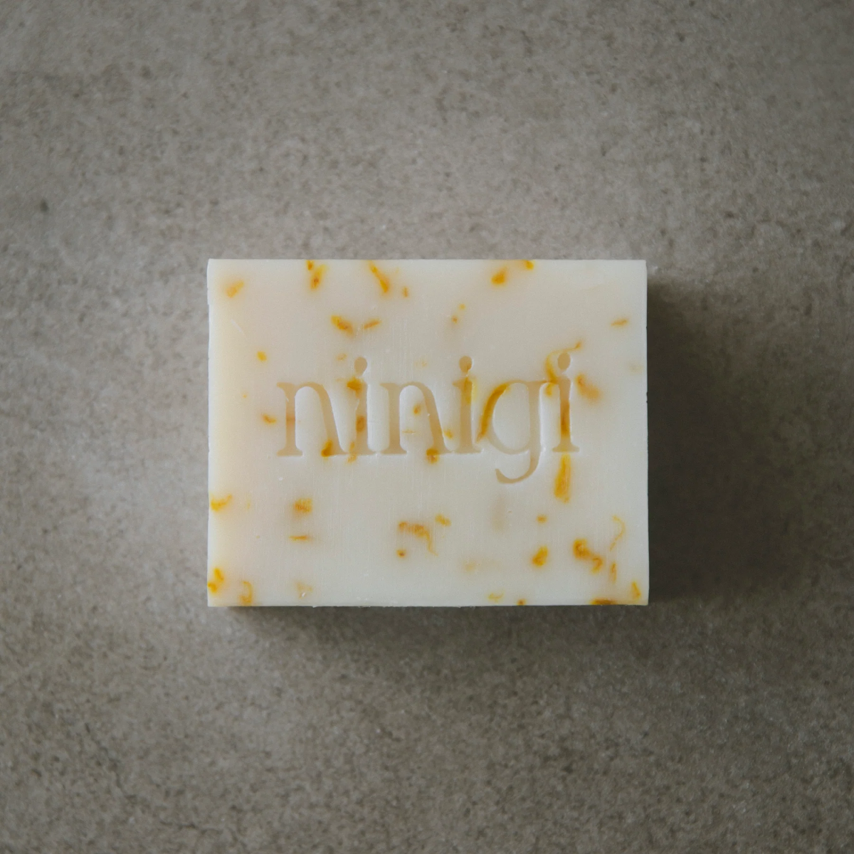 Bar of soap with 'ninigi' branding on a gray background